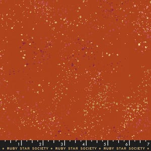 Puede incluir: Tela de color óxido con un patrón moteado. La tela presenta pequeños puntos irregulares en tonos crema, rosa y morado dispersos por la superficie. El texto "RUBY STAR SOCIETY" está en la parte inferior.