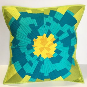 Może przedstawiać: Poduszka dekoracyjna w zielono-niebieskim wzorze geometrycznym z żółtym środkiem.