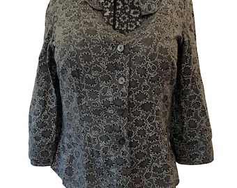 Blusa semitransparente con estampado floral negro y verde y botones.