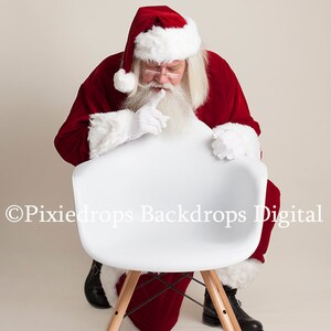May include: Santa Claus in a red suit with white trim and a white beard is peeking over the back of a white chair with wooden legs. The chair is on a white background.