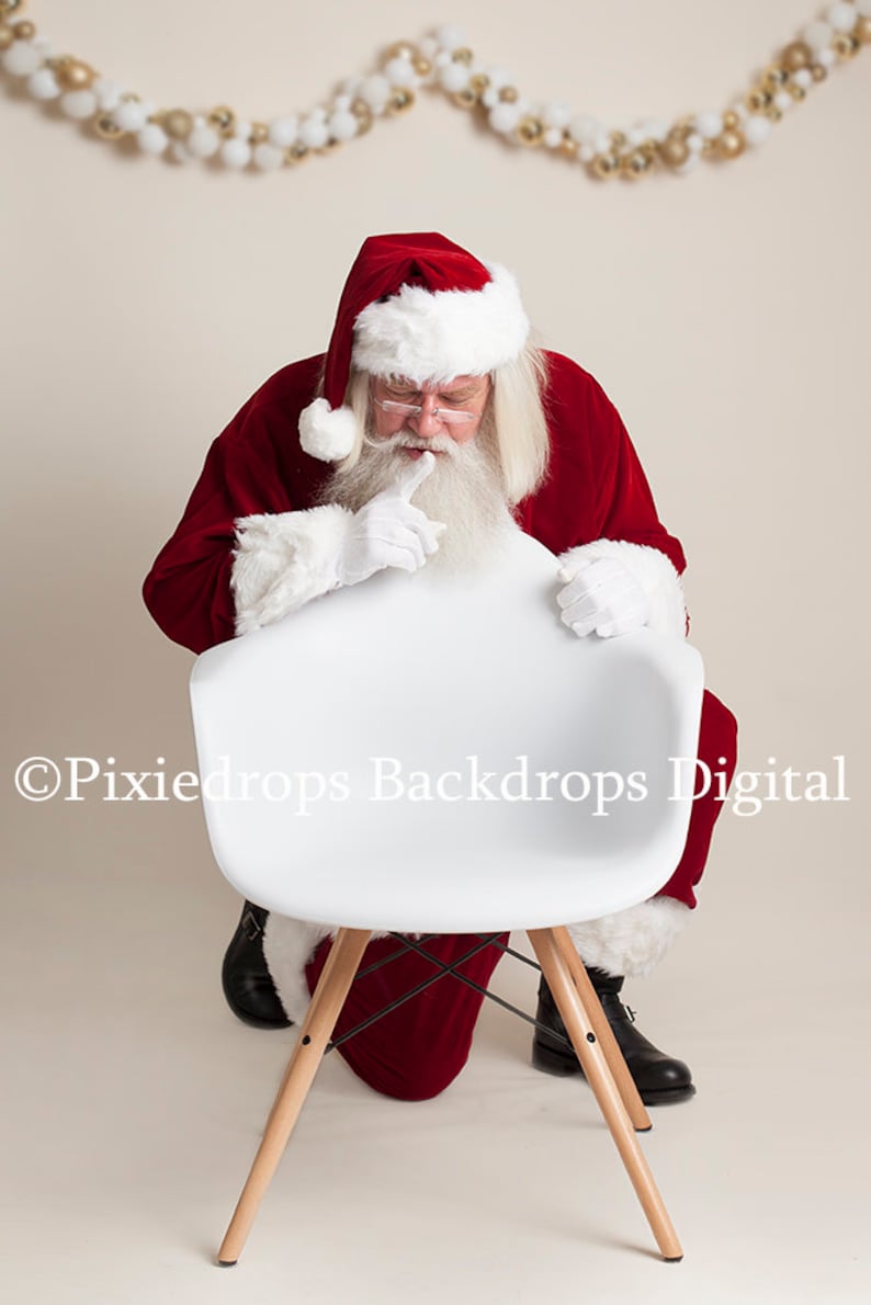 May include: Santa Claus in a red suit with white trim and a white beard is peeking over the back of a white chair with wooden legs. The chair is on a white background.