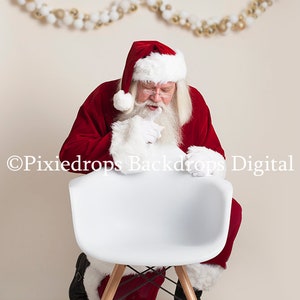 May include: Santa Claus in a red suit with white trim and a white beard is sitting on a white chair with wooden legs. He is looking down at the chair with a thoughtful expression.
