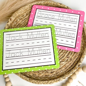 May include: Two green and pink dry-erase boards with white polka dots. The boards have dotted lines for practicing writing the names "Jack Mullen" and "Grace Mullen".