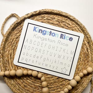 May include: White dry-erase board with the text "Kingston Rice" and the alphabet written in uppercase and lowercase letters. A star is in the bottom right corner.