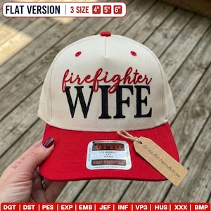 Puede incluir: Una gorra de b&eacute;isbol color crema con visera roja que presenta el texto bordado en rojo "firefighter" sobre el texto negro "WIFE". Una pegatina rectangular en la visera dice "OTTO CLASSIC FIT OSFM MID PROFILE" y una etiqueta marr&oacute;n "ShopArchersArrow".