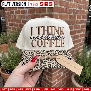 Puede incluir: Una gorra de béisbol color crema con visera de estampado de leopardo. El frente presenta un bordado en marrón y negro con el texto I THINK i need more COFFEE. Una etiqueta de papel marrón con el nombre ShopArchersArrow está unida a la visera.