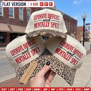 Puede incluir: Tres gorras de béisbol color crema con texto bordado en rojo EXPENSIVE DIFFICULT and MENTALLY SPICY. Las gorras tienen viseras con estampado de leopardo y están disponibles en tamaños de 10,16 cm, 12,7 cm y 15,24 cm indicados arriba.