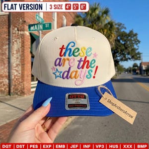 May include: A cream-colored baseball cap with a blue brim featuring the embroidered text "these are the days!" in multi-colored script. The cap includes a silver and black Otto brand sticker on the brim and a tan cardboard tag reading ShopArchersArrow.