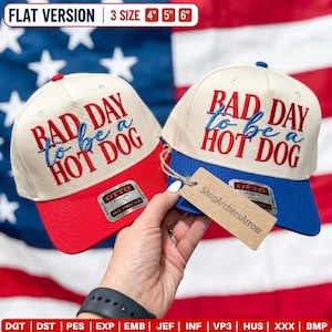 May include: Two baseball caps with cream-colored crowns and red or blue brims. The text 'BAD DAY to be a HOT DOG' is embroidered in red and blue on the front. Each cap features an Otto brand sticker and a brown cardboard tag labeled ShopArchersArrow.