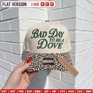 May include: A cream-colored trucker hat with a leopard print brim and dark green embroidered text that reads Bad Day To Be A Dove. The hat features an Otto brand sticker and a brown paper tag labeled ShopArchersArrow, with 4, 5, and 6 inch sizes.