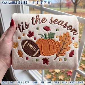 May include: A cream-colored fabric featuring an embroidered design with the text 'tis the season' in brown. The graphic includes a brown football, an orange pumpkin, and various red, orange, and yellow autumn leaves, available in 4, 5, 6, 7, and 8 inch sizes.
