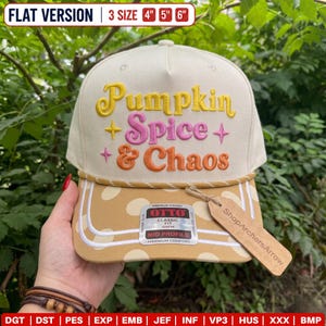 May include: A cream-colored baseball cap featuring the embroidered text Pumpkin Spice & Chaos in yellow, pink, and orange with star accents. The brim is tan with white polka dots and a braided cord trim. Includes an Otto brand sticker and tag.