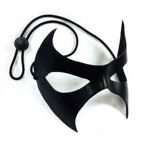 K&ouml;nnte beinhalten: Eine schwarze Leder-Maskenballmaske mit spitzem Design und einem schwarzen Gummiband.