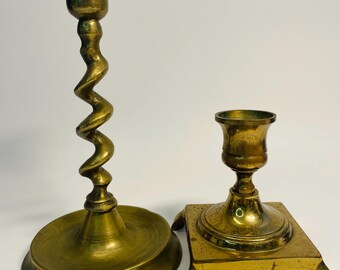 Par de candelabros antiguos de latón, con patas de diseño asimétrico y forma retorcida.