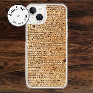 May include: A clear iPhone case with a tan, textured design resembling ancient cuneiform writing. The case is designed for iPhones 14 and up, with a MagSafe circle on the top left. The case is on a dark wood grain surface.