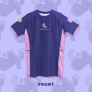 May include: A navy blue t-shirt with pink side panels and sleeve trim. The shirt features the text "SWEATY ROLLS CLUB" and cartoon graphics of a swan and other characters. The word "FRONT" is printed at the bottom.