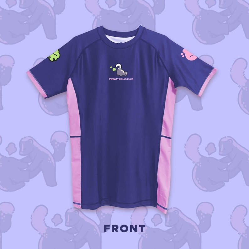 May include: A navy blue t-shirt with pink side panels and sleeve trim. The shirt features the text "SWEATY ROLLS CLUB" and cartoon graphics of a swan and other characters. The word "FRONT" is printed at the bottom.