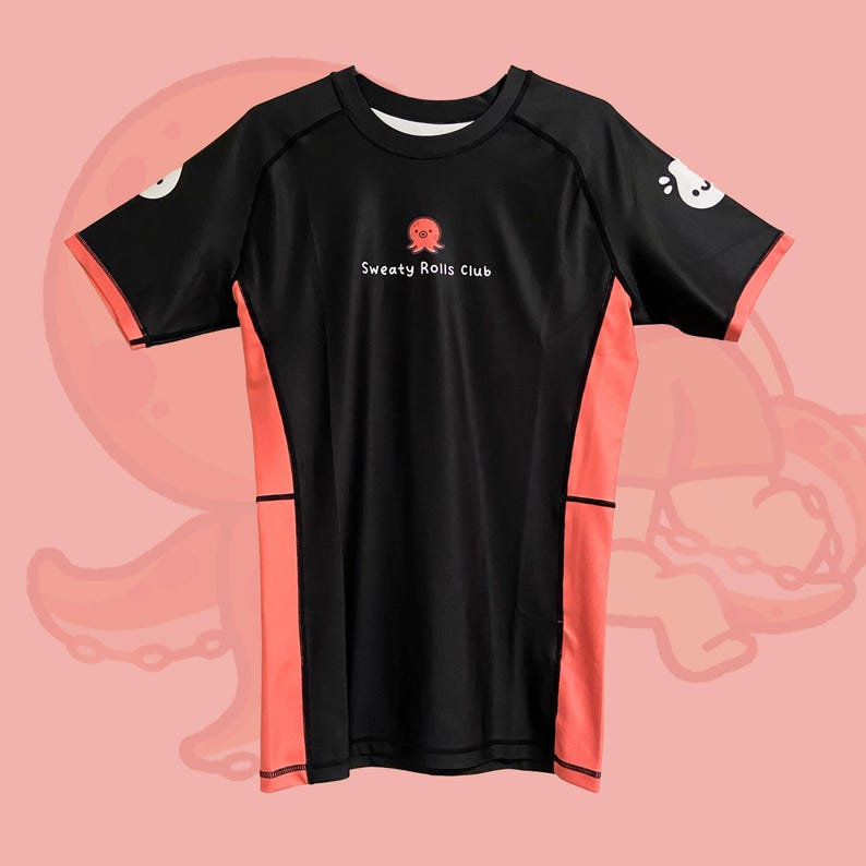 May include: Black athletic t-shirt with coral side panels and sleeve trim. The shirt features a small octopus graphic above the text "Sweaty Rolls Club" on the chest. White cartoon octopus graphics are on the sleeves.