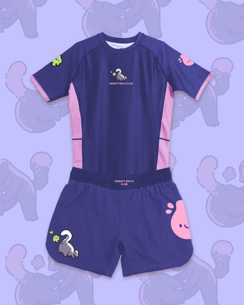 May include: A navy blue athletic set featuring a short-sleeved top and matching shorts. The top has pink accents and the text "SWEATY ROLLS CLUB". The shorts also have the text "SWEATY ROLLS CLUB". Both pieces have cartoon graphics.