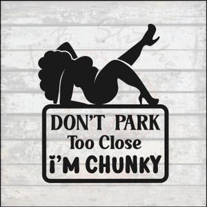 May include: Black sign with a silhouette of a woman reclining on a rectangular sign. The sign reads "DON'T PARK Too Close I'M CHUNKY" in white text. The background is a light wood grain pattern.