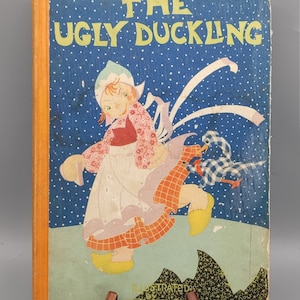 Könnte beinhalten: Vintage Kinderbuch mit dem Titel "Das hässliche Entlein". Das Cover zeigt eine Illustration eines jungen Mädchens in holländischer Tracht und ein Entlein. Der Titel ist in grünen Buchstaben auf blauem Hintergrund mit weißen Punkten.