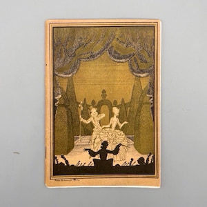May include: A vintage booklet featuring a black and gold illustration of a stage scene. The illustration shows two figures in period dress on a stage, with a conductor in the foreground. The background depicts a garden setting.