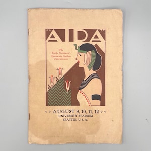 May include: A vintage programme cover for the opera "Aida." The design features a profile of a woman in Egyptian-style attire, set against a brown background. Text includes "AIDA," "August 9, 10, 11, 12," and "University Stadium, Seattle, U.S.A."