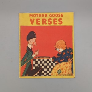 Könnte beinhalten: Ein Vintage-Buchcover mit dem Titel "Mother Goose Verses" in gelben Buchstaben auf rotem Hintergrund. Das Cover zeigt eine Comic-Illustration eines Mannes und einer Frau, die ein Spiel auf einem Schachbrett spielen.