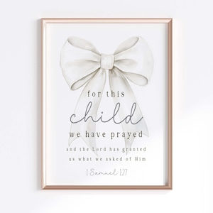 Pode incluir: Um laço branco de aquarela com uma citação sobre a oração por uma criança. A citação diz "por esta criança oramos e o Senhor nos concedeu o que lhe pedimos 1 Samuel 1:27".
