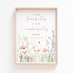 Può includere: Uno sfondo bianco con una cornice di legno attorno a una stampa con fiori rosa e foglie verdi. La stampa dice "Sono fatto in modo tremendo e meraviglioso" con il riferimento biblico "Salmo 139:14" sotto.