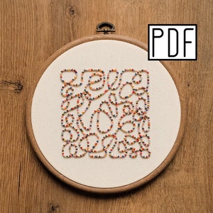 Puede incluir: Un bastidor de bordado circular de madera que contiene tela de color blanco roto con un diseño cuadrado hecho de cuentas de semillas multicolores dispuestas en un patrón de línea abstracta, sinuosa y continua. Incluye un cuadro de texto PDF.