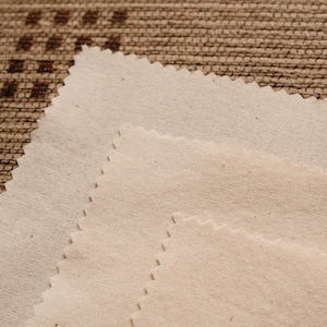 Peut inclure: Trois couches de tissu blanc cassé avec une texture subtile. Le tissu est plié en quinconce, créant un effet de superposition.