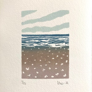 May include: A blue and brown linocut print of a seascape with three horizontal lines of clouds above the water. The print is signed "1/22" and "Mo-22" in the bottom corners.