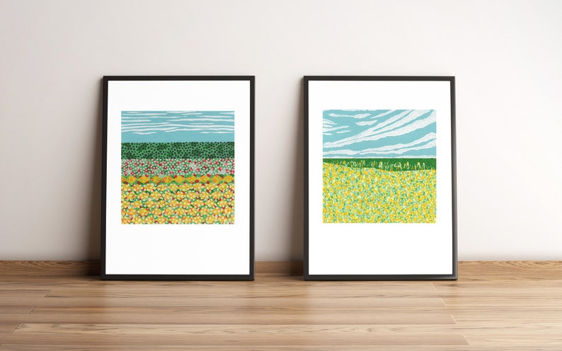 May include: Two framed prints of abstract landscape paintings. The left print features a green, red, and yellow field with a blue sky. The right print features a green field with a blue sky and white clouds.