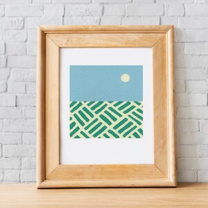 May include: A framed print of an abstract landscape with a light blue sky, a white sun, and a green and yellow patterned field.