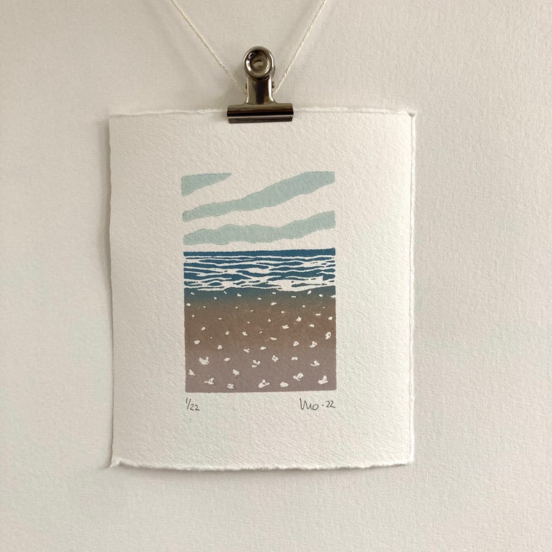 May include: A blue and brown print of a seascape with a light blue sky and white clouds. The print is signed and dated "1/22" and "Wo-22".