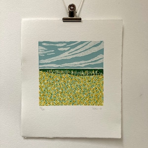 May include: A print of a landscape with a field of yellow flowers under a blue sky with white clouds. The print is numbered 19/20 and dated 2021.