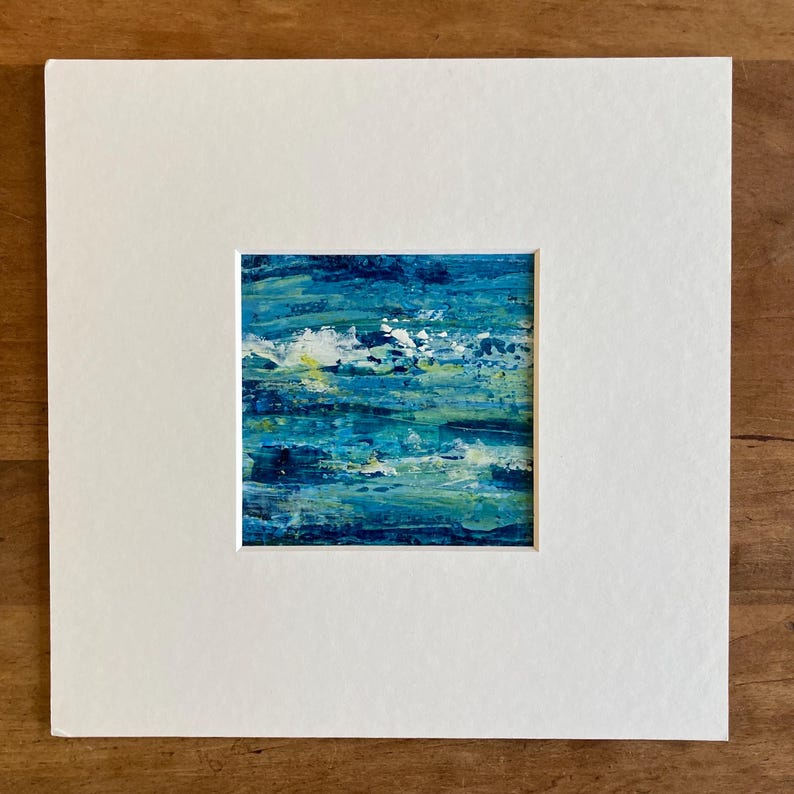 Puede incluir: Pintura abstracta de un paisaje marino azul y verde con acentos blancos. La pintura est&aacute; enmarcada en un passe-partout blanco.