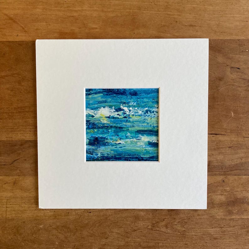 Puede incluir: Una pintura abstracta enmarcada con pinceladas azules, verdes y blancas. La pintura est&aacute; sobre un fondo blanco.