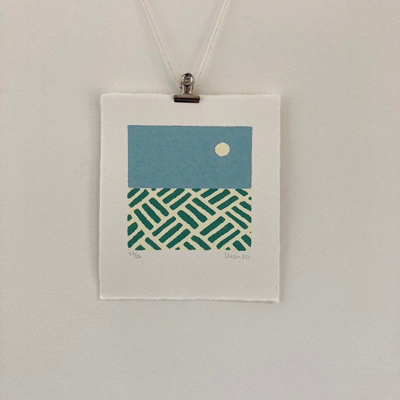 May include: A blue and green abstract print with a white circle in the upper portion of the blue section. The print is signed "23/26" and "11-20".