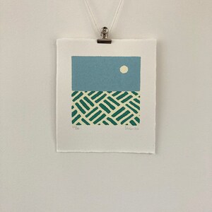 May include: A blue and green abstract print with a white circle in the upper portion of the print. The print is signed "LW 20" and numbered "23/26".
