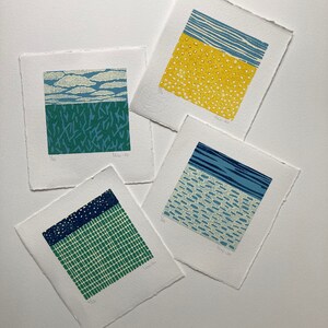 May include: Four small, square prints with different abstract patterns in blue, green, yellow, and white. The prints are numbered 1/26, 1/26, 1/26, and 1/26.