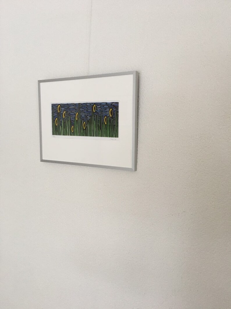 May include: A framed print of a landscape with yellow flowers and green grass against a blue sky. The print is titled "Morning Glory" and is signed by the artist.