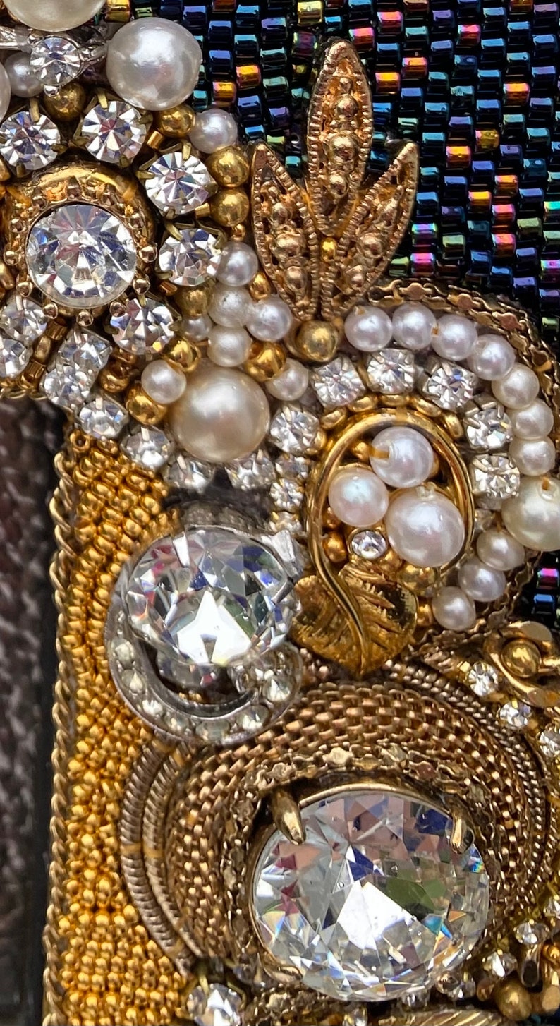 May include: Close-up of a gold and silver beaded frame with white pearls and clear rhinestones. The frame is decorated with a gold leaf design.