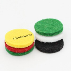 May include: Four round felt pads in green, white, black, and yellow colors. The pads are stacked on top of each other. The text "LDjewelrycharm.Etsy" is printed on the yellow pad.