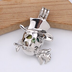 May include: Silver charm featuring a skull wearing a top hat and holding a flower. The skull is hollow and can be used as a charm for a necklace or bracelet.
