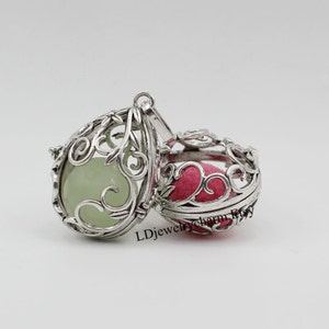 May include: Two open silver-colored filigree pendants. One is teardrop-shaped with a light green stone inside. The other is round with a pink insert. The text "LDjewelrycharm Rtsy" is visible on the bottom right.