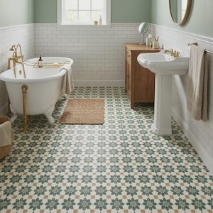 May include: A bathroom featuring a white clawfoot bathtub with gold taps, a pedestal sink, and a wooden cabinet. The floor has a patterned tile design in green, beige, and brown. A woven mat is in front of the tub.
