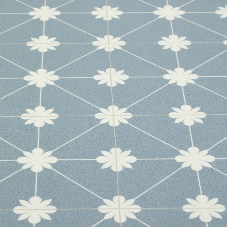 May include: Close-up of a blue tile surface with a repeating pattern of white daisy-like flowers and connecting lines. The tiles are arranged in a grid, creating a geometric design. The overall effect is clean and modern.