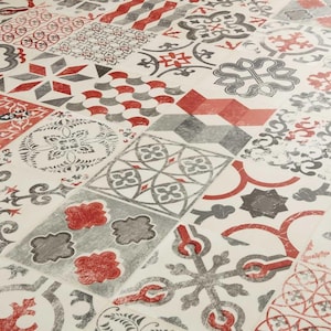 Puede incluir: Primer plano de una superficie de baldosas estampadas. El diseño presenta un mosaico de motivos geométricos y florales en rojo, gris y blanco. Las baldosas están dispuestas en un patrón repetitivo, creando una superficie visualmente interesante.
